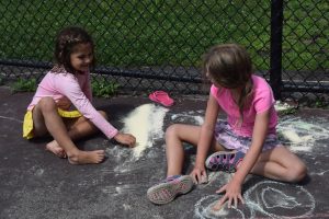 kids playing with chalk on the sidewalk