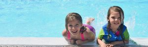 kids in swimming pool smiling at camera