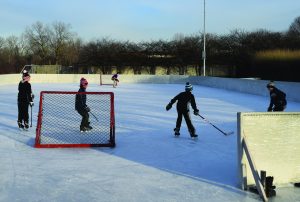 kids playing ice hockey on the rtpd outdoor rink in winter