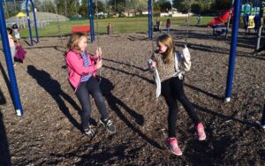 girls talking while sitting on swings