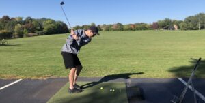 man swinging golf club at driving range