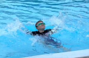 Child with goggles swimming in pool
